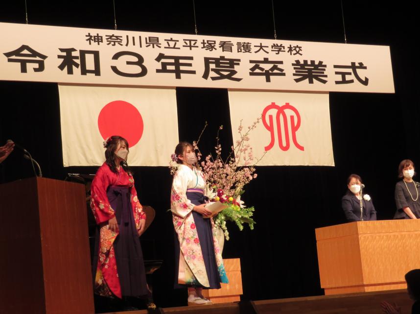 卒業生2人が壇上に上がっている写真