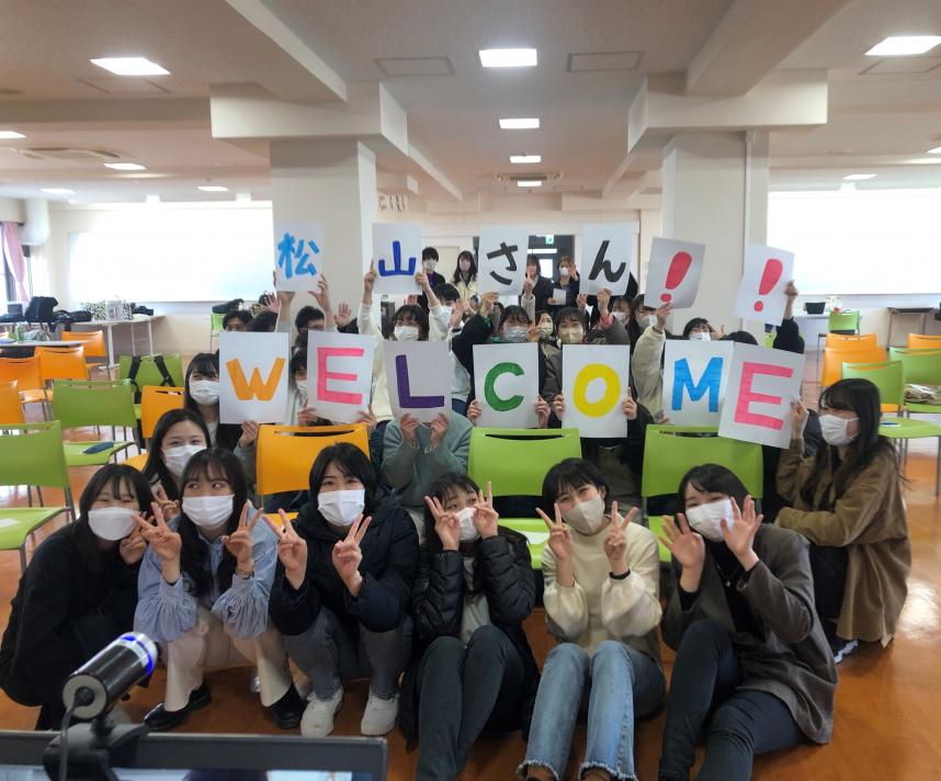 学生が松山さんWELCOMのボードを持っている写真