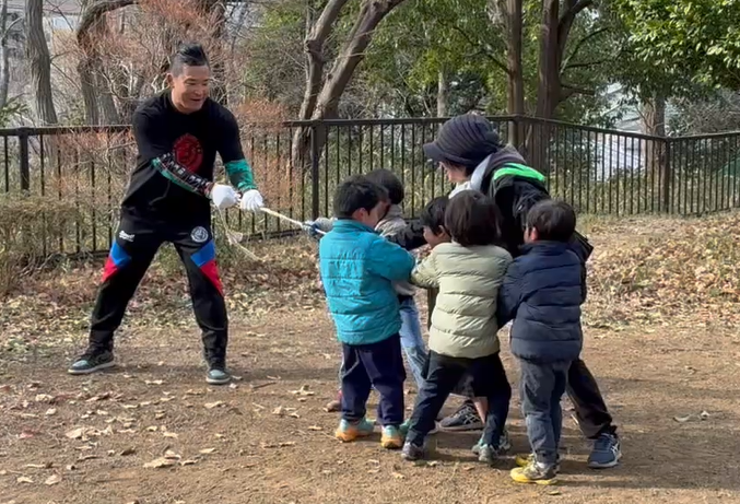 子どもたちと綱引きをするKUSHIDA選手