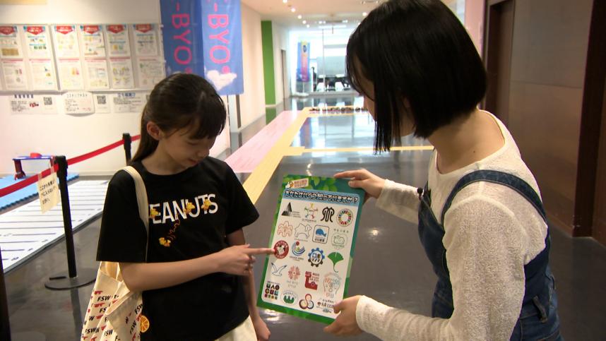 神奈川県ゆかりのロゴ・マークについてインタビューを行う井上ゆみ乃リポーター