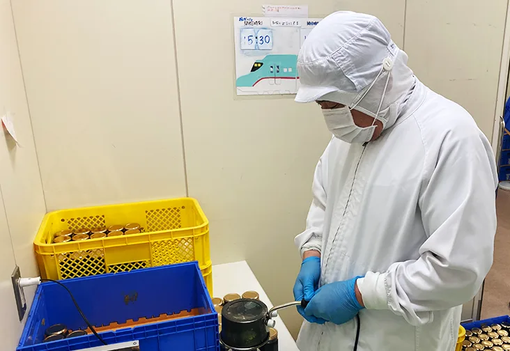 トマトジュースの瓶のキャップ閉め作業をしている写真