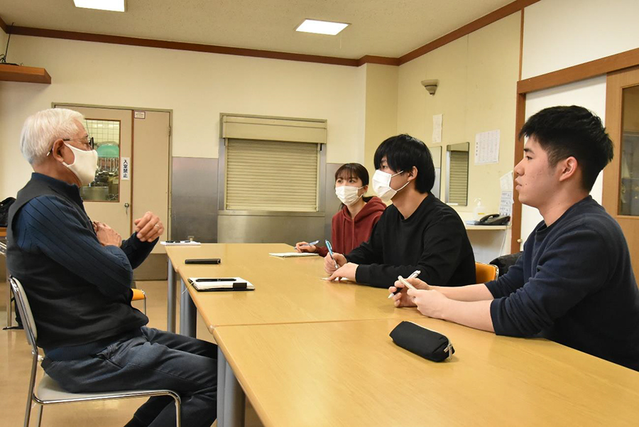 卒業論文のために光友会の一杉好一さん（左）からユニバーサル農園の話を聞く東海大学の学生。手前から井上大志さん、関口栄心さん、山口あかねさん。